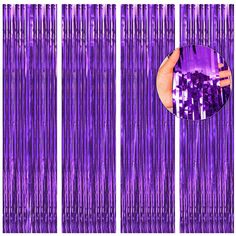 a hand is holding a purple object in front of some metallic foil fringes that are hanging from the ceiling