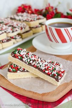 two pieces of chocolate and sprinkles on a plate next to a cup of coffee