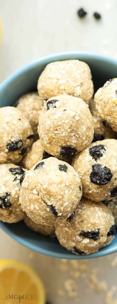 a blue bowl filled with oatmeal raisin energy bites next to sliced lemons