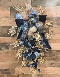 a blue and gold christmas wreath hanging on a wooden wall