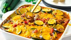 a casserole dish with zucchini, cheese and sauce in it on a table