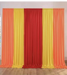 an orange, yellow and red curtain is in the middle of a room with wooden floors