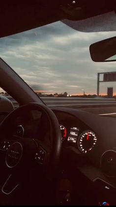 the dashboard of a car driving on a highway at dusk with traffic signs in the distance