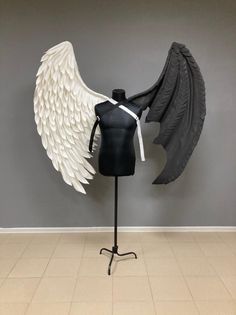 a mannequin with black and white wings on display in front of a gray wall