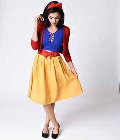 a woman in a yellow dress and red cardigan is posing for the camera with her hand on her hip