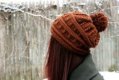 a woman with long hair wearing a knitted beanie hat in the wintertime