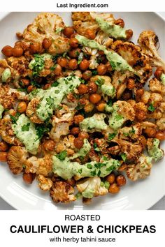 roasted cauliflower and chickpeas with herby tahini sauce on a white plate