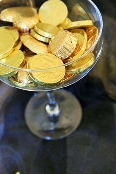 a glass filled with gold coins on top of a table