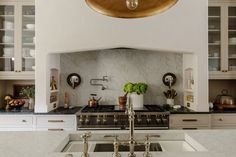 a kitchen with marble counter tops and gold accents on the hood over the stove top