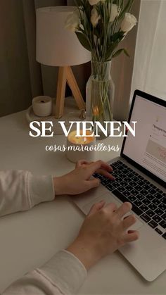 a woman is typing on her laptop with flowers in the vase next to her and text that reads se vienen