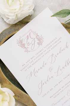 a close up of a wedding card on a table with flowers