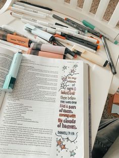 an open book sitting on top of a white chair next to markers and pencils