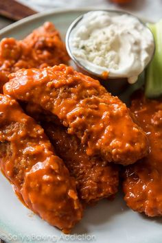 a plate with chicken wings, coleslaw and pickles on it next to a bottle of mayonnaise