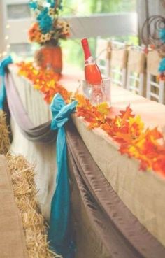 the table is decorated with fall leaves and wine bottles on top of hay bales