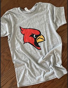 These Cardinal head shirts are a perfect addition to your school spirit wear!   ❗️Sizes: Toddler-2T-5T  Youth XS-XL  Adult S-XL  Adult 2X Adult 3X Available in short sleeve, long sleeve and sweatshirts!  Shirts are all unisex sizing! Colors available in red, gray, charcoal gray, white and black!  The shirt has a cardinals head printed and pressed onto the shirt!  If you would like to request a custom order, please send us a message!! Casual Athletic Heather T-shirt For Game Day, Team-colored Tops With Mascot For School Spirit, Team-colored Mascot Tops For School Spirit, College Mascot Team-colored Tops, Cotton T-shirt With Mascot For Fan Gear, Collegiate Mascot T-shirt For Fan Gear, Collegiate T-shirt With Mascot For Fan Gear, Casual Gray Top For Game Day, Collegiate Style T-shirt With Mascot For Fans