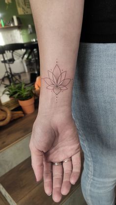 a woman's hand with a small lotus tattoo on the left side of her wrist