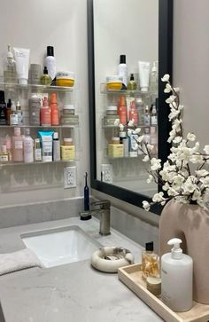 a bathroom sink with soaps, lotions and bottles on the shelves above it