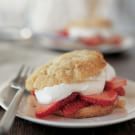 a strawberry shortcake on a white plate with a fork and knife next to it