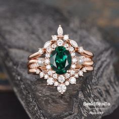 a close up of a ring with a green stone in the middle and white pearls around it