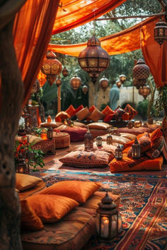 an outdoor area with lots of pillows and lights hanging from the ceiling, surrounded by orange drapes