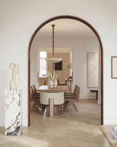 an arch in the middle of a room with chairs and a dining table on it