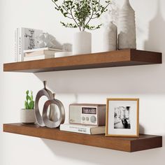 two wooden shelves with pictures, vases and other items on them in a white room