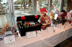 the table is set up with many items for sale in front of large glass windows