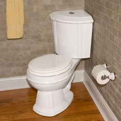 a white toilet sitting in a bathroom next to a wooden floor