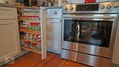 a stainless steel oven in a kitchen with spice racks on the wall and wooden flooring