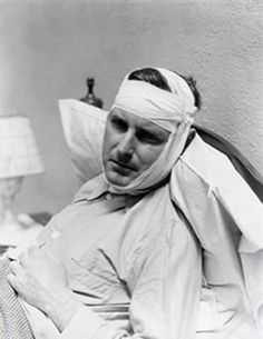 an old photo of a man laying in bed with a cast on his face and head