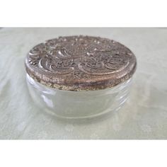 an old silver and glass box sitting on a white tablecloth