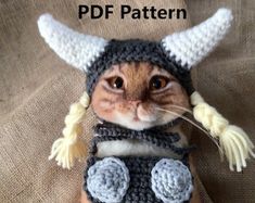 a cat wearing a knitted hat and scarf with horns on it's head