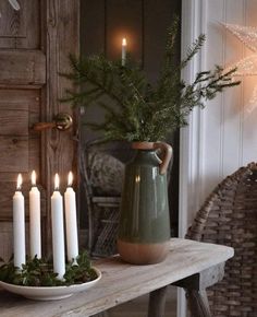 a table topped with candles and a vase filled with greenery on top of it