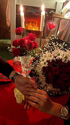 two people sitting at a table with flowers and candles