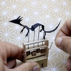 two hands are working on some type of mechanical device that looks like a bird and dragon