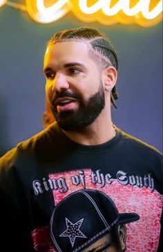 a man wearing a black shirt with a star on it and braids in his hair