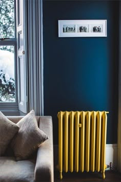 a living room with blue walls and a yellow radiator next to a couch