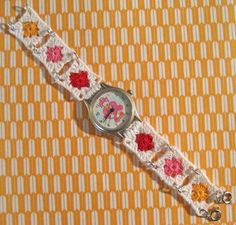 a watch with crocheted flowers on it sitting on a yellow and white background