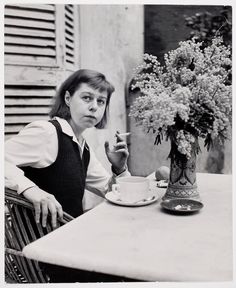 a woman sitting at a table with a cup and saucer in front of her