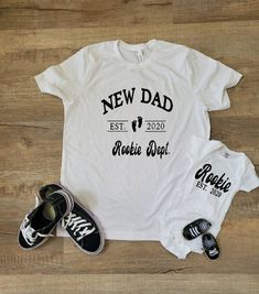 "This listing is for ONE Unisex Adult Shirt that says \"New Dad\" and ONE child size that says \"Rookie\". Please leave a note at checkout with the shirt color you want for the adult shirt. If you need additional shirts please let the shop know! T-shirt Details: unisex standard fit shirt » Deep Heather is 52/48 combed and ringspun cotton/polyester, » Sport grey and Black Heather are 90/10 combed and ringspun cotton/polyester » Prism Colors: 99% combed and ring-spun cotton, 1% polyester » light c White Shirt With Text Print For Family, Father's Day Shirt With Name Print And Relaxed Fit, Father's Day Shirt With Name Print In Relaxed Fit, White Top With Custom Parenting Print, White Top With Custom Print For Parenting, White Tops With Custom Parenting Print, White Tops With Custom Print For Parenting, Baby Moses, Papa Shirts