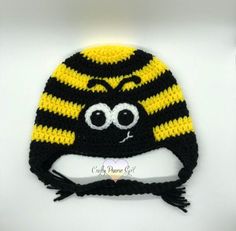 a crocheted hat with eyes and a black, yellow and white striped design