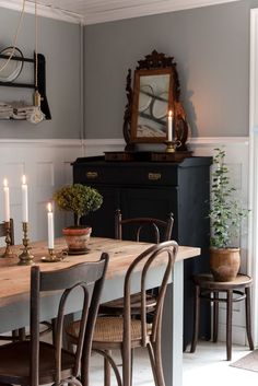 a dining room table and chairs with candles on it in front of an old dresser