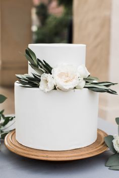 a white wedding cake with flowers and greenery