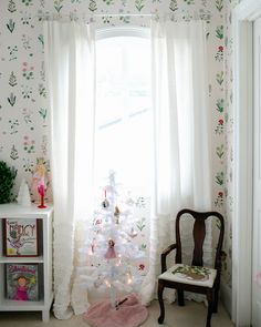 a white christmas tree sitting in the corner of a living room next to a window