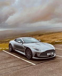 a silver sports car parked in a parking lot next to a field with brown grass