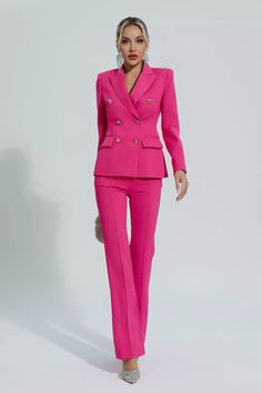 a woman in a bright pink suit and heels standing on a white surface with her hands behind her back