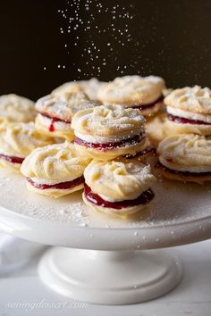 a white cake plate topped with cookies covered in powdered sugar and jelly toppings