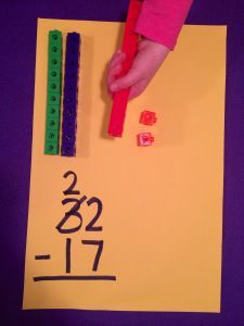 a child's hand holding a pencil over a piece of paper with numbers on it