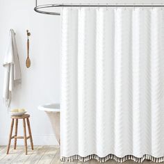 a white shower curtain in a bathroom next to a bathtub and wooden stools