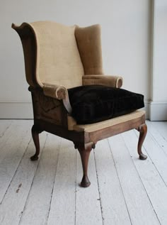 an old chair with a black pillow on it's back in a white room